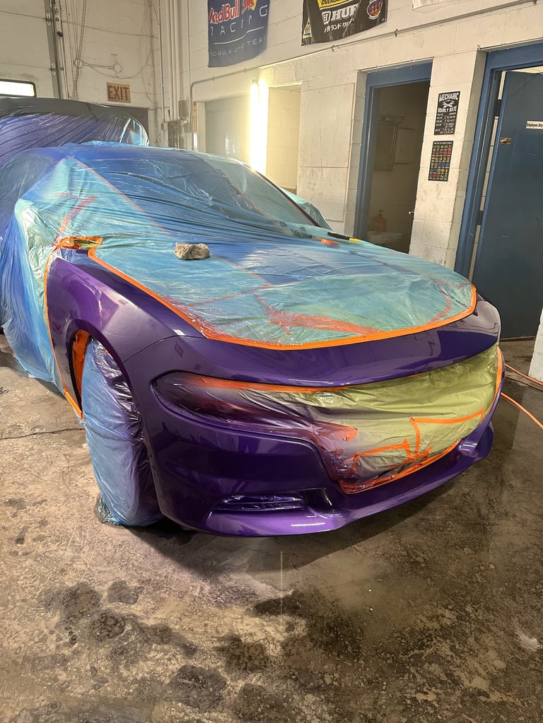 Purple sports car covered with colorful protective wrap in a garage workshop setting
