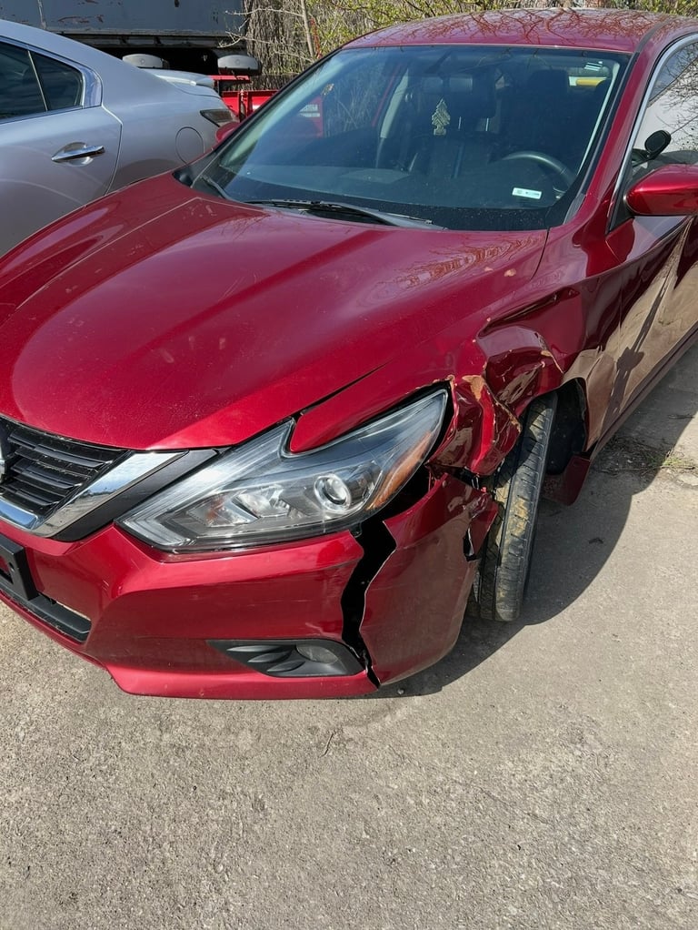 Red sedan with significant damage to the right front fender and door in a parking lot